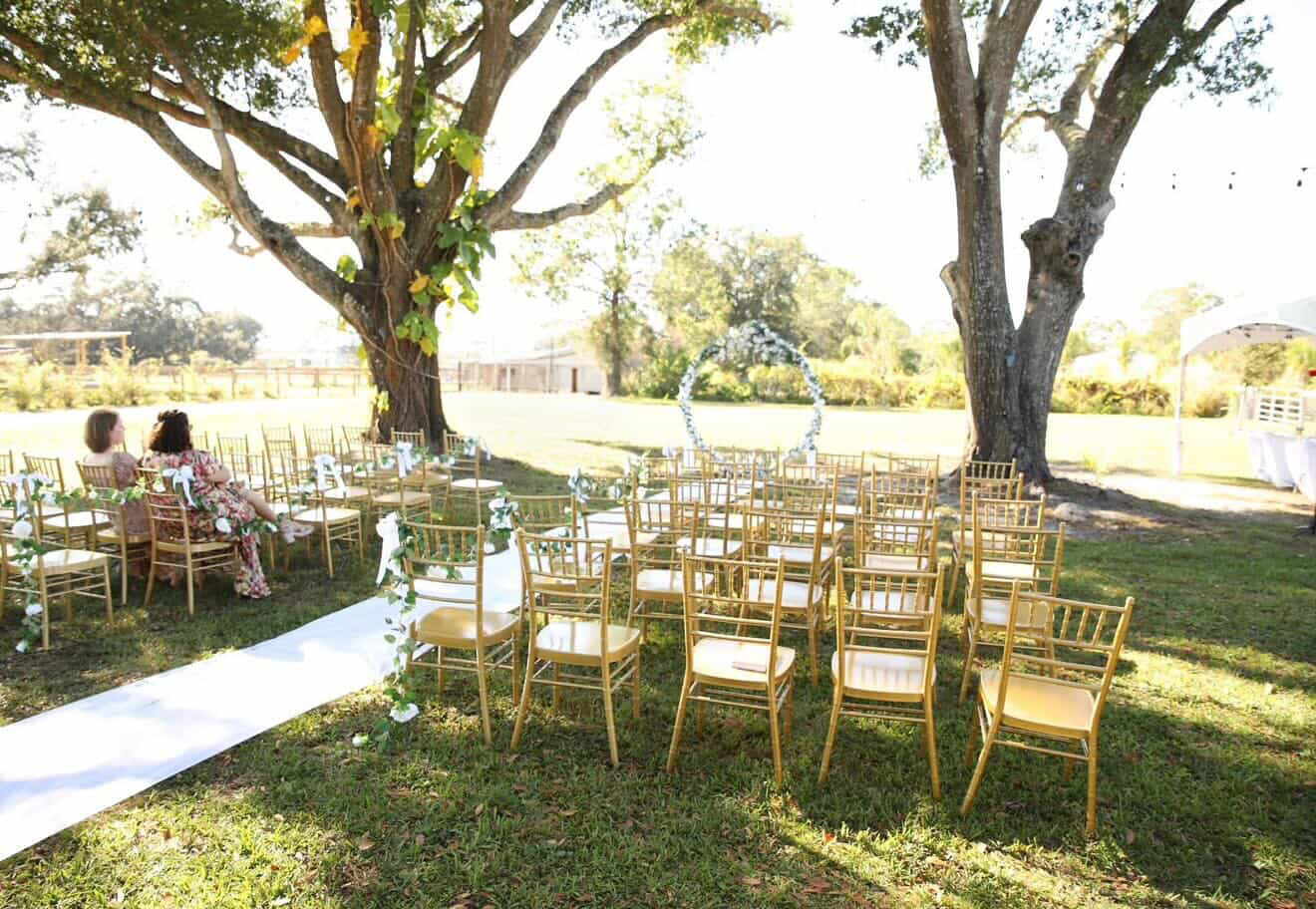 A walkway lined with chiavari chairs at a wedding ceremony.